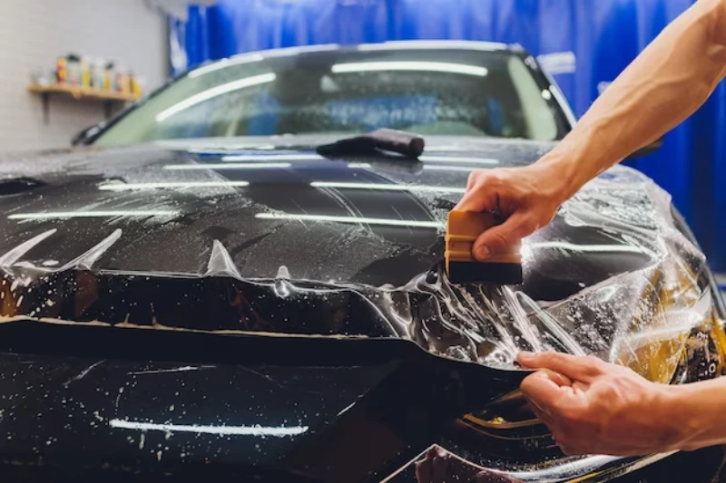 A black sports car being installed with a clear PPF