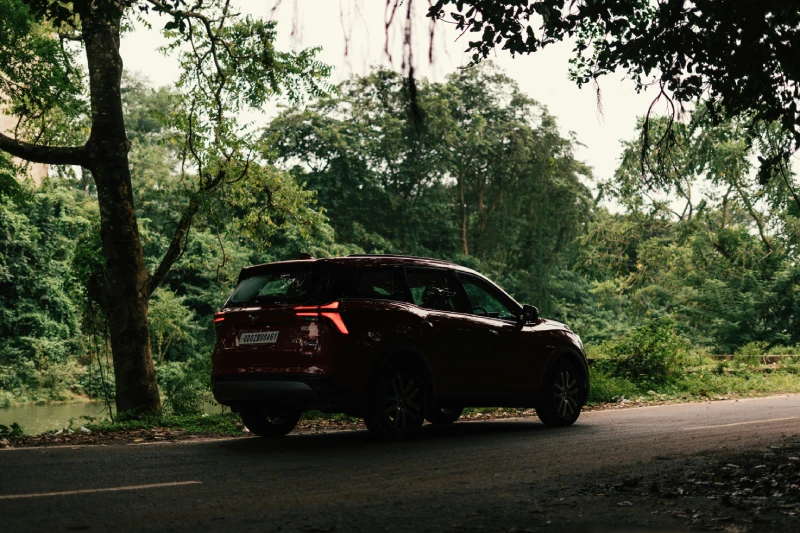 A maroon red Mahindra XUV parked beside a country road