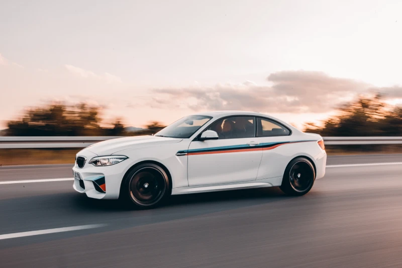 A white sedan speeding through the road in the countryside