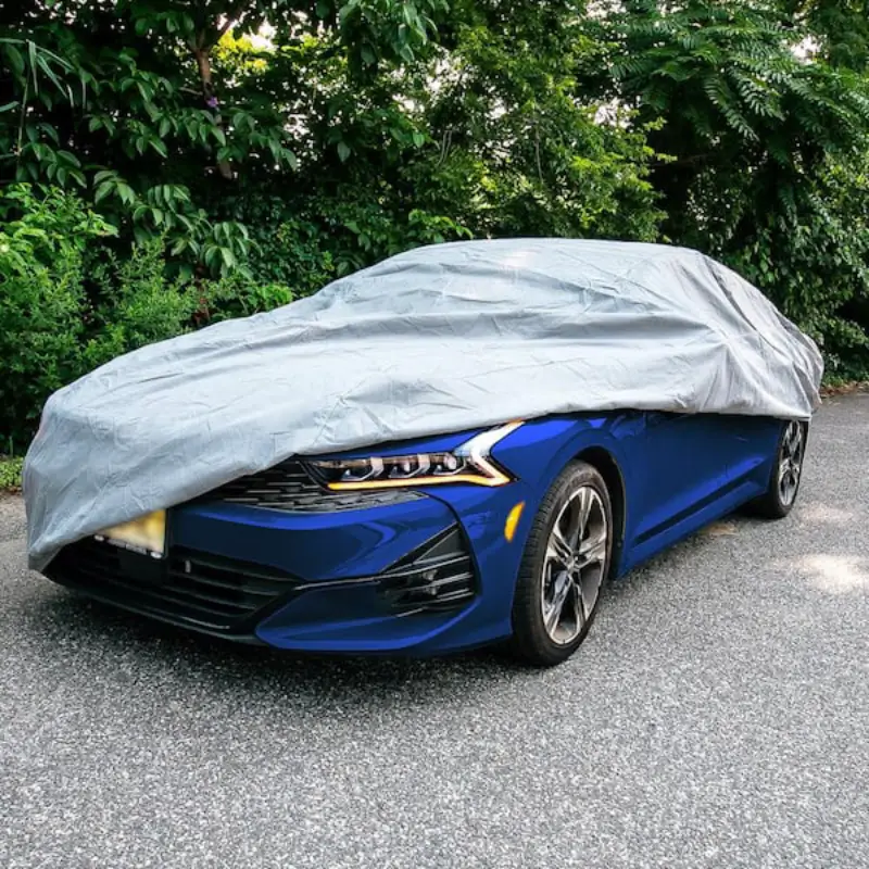 A blue-coloured car covered with a plastic car cover