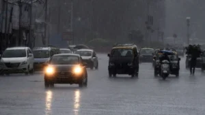An Indian street with multiple cars driving during rains