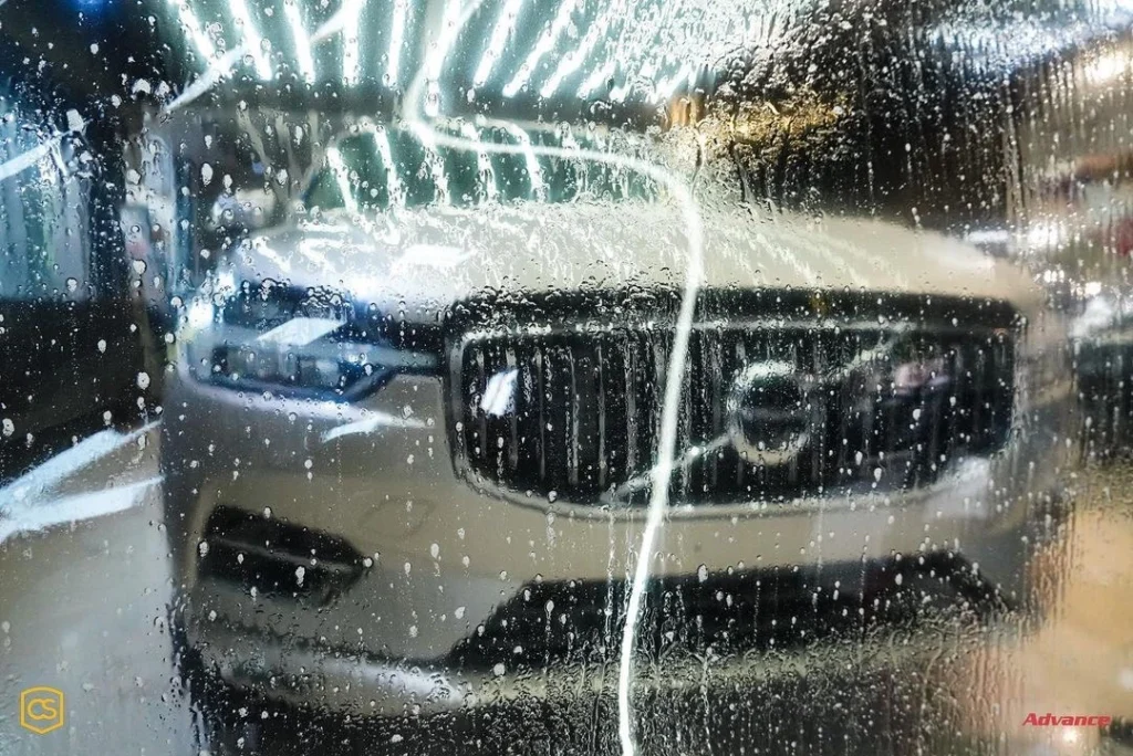 A silver Volvo SUV is visible from a PPF with water sprayed on it, held in front of it