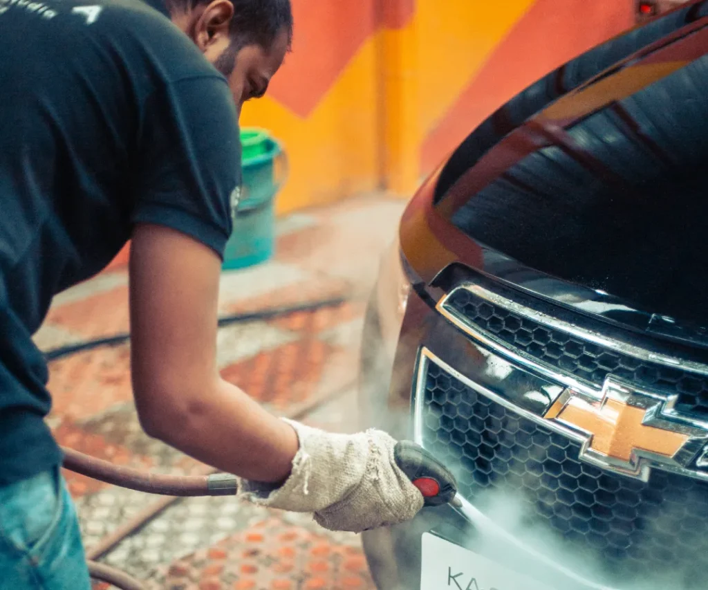 a man polishes a Chevrolet hatchback inside a detailing studio