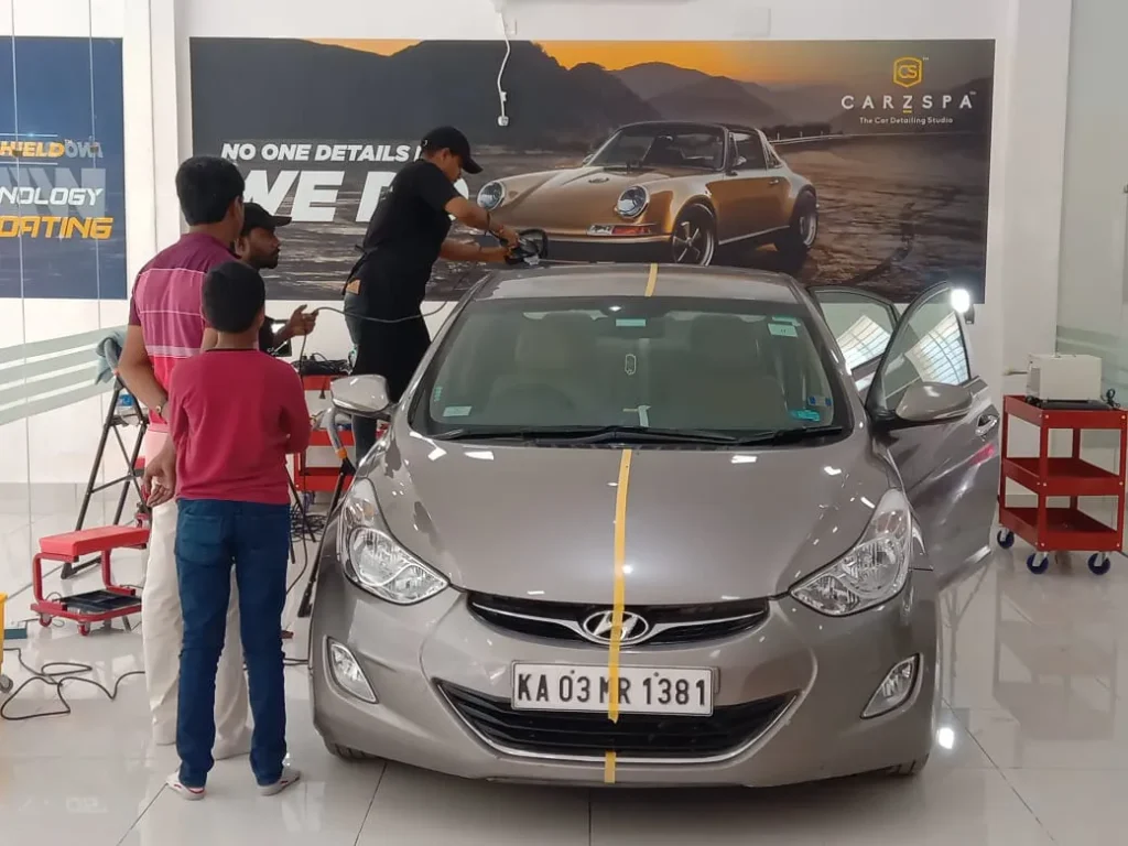 Workers work on a car inside a detailing studio