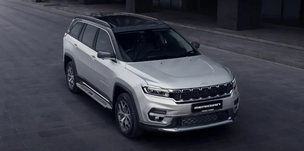 An image of a grey and black coloured Jeep Meridan driving across a cemented complex road