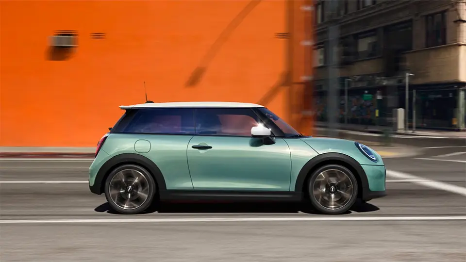 A woman drives a Mini Cooper S through a street in Italy