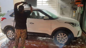 A white coloured car being washed by a worker at a CarzSpa