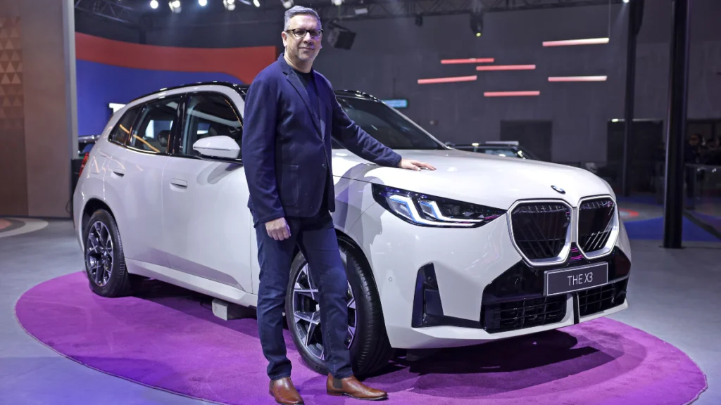 A man stands next to the newly launched BMW X3 luxury SUV at the Bharat Mobility Expo 2025