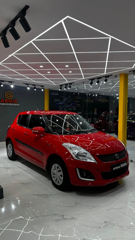 A bright red coloured car parked inside a detailing studio