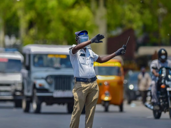 A traffic policeman manages traffic while vehicles pass from a Chennai street on a hot afternoon