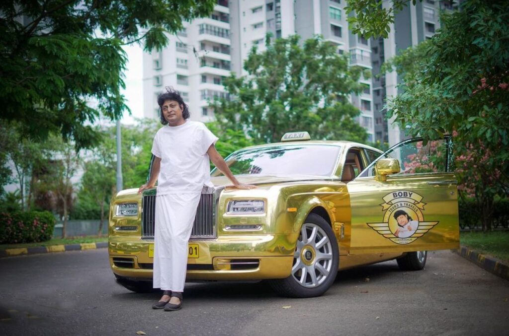 Prominent businessman Boby Chemmanur poses in front of his golden Rolls Royce Phantom, which has his business logo imprinted on its door Caption: Source: India.com