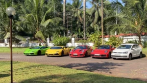 A row of luxury cars and a hatchback parked outdoors somewhere in Kerala on a sunny day