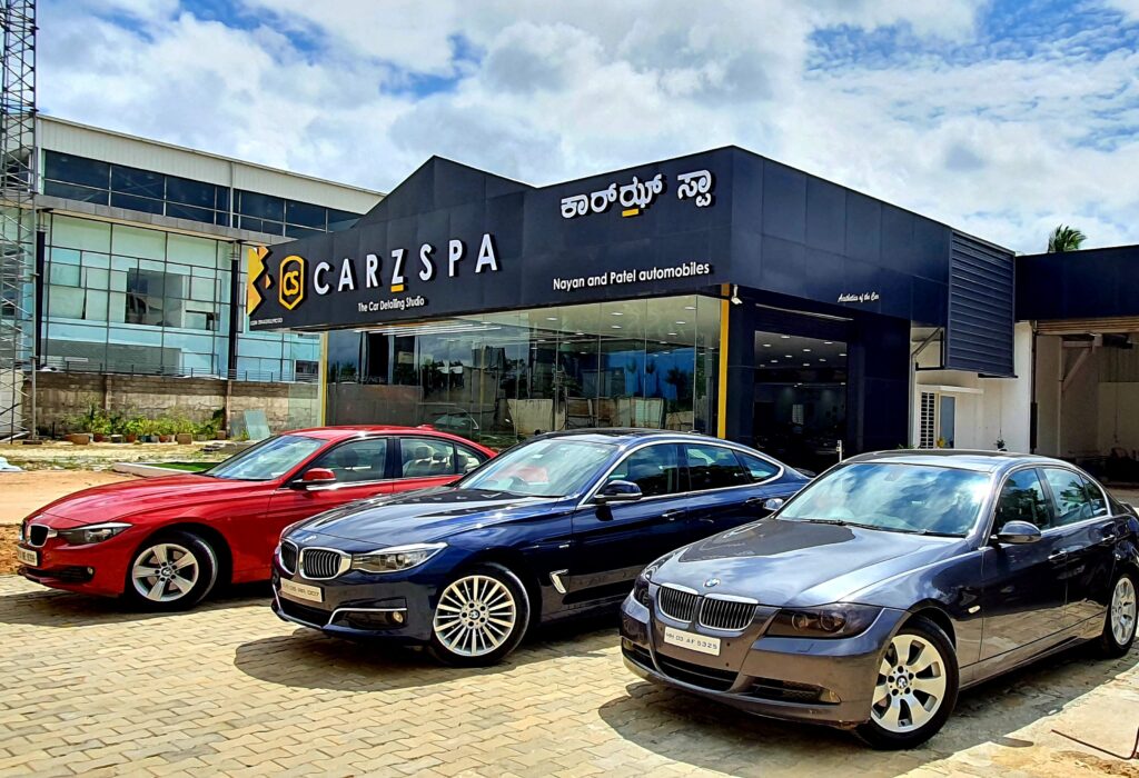 Three luxury cars parked outside an automotive franchise outlet located somewhere in South India