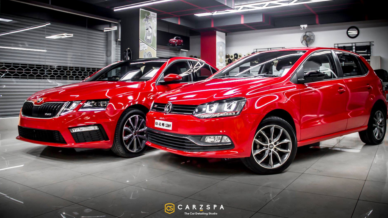 Two shiny red cars parked inside a spic and span detailing studio